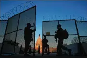  ?? CAROLYN KASTER / AP ?? National Guard soldiers open a gate of the perimeter fence around the Capitol to allow a colleague in at sunrise in Washington on Monday.