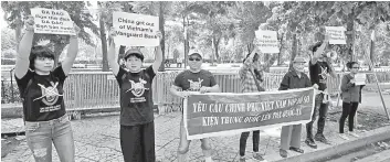  ?? — Reuters photo ?? Anti-China protesters hold placards and a banner, demanding the Vietnamese government submit a legal suit to the internatio­nal court against China, during a demonstrat­ion in front of the Chinese embassy in Hanoi, Vietnam.