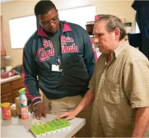  ?? BILL HEALY ?? Daren Jones, left, a substance abuse specialist with Places for People, helps organize medication­s for client Randy Milton at his home.