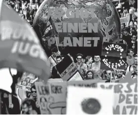  ?? JOHN MACDOUGALL/GETTY-AFP ?? People walk with a globe reading “There is no Planet B” during a demonstrat­ion in Berlin.