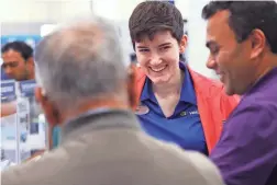  ??  ?? Best Buy Verizon expert Skyler Dolihite smiles as she helps customers as Thanksgivi­ng Day shoppers hit the Best Buy store right after it opened.