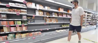  ?? Agence France-presse ?? ↑
A shopper walks past partially-filled shelves in a supermarke­t at Nine Elms, south London, on Thursday.