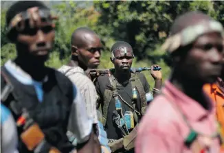  ?? JEROME DELAY/THE ASSOCIATED PRESS ?? Christian militiamen walk through a forest clearing outside Central African Republic’s capital Bangui on Sunday. The leader of the militia says his fighters won’t put stop their rebellion until Muslim President Michel Djotodia is gone from power,...