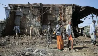  ?? Picture:Tiksa Negeri, Reuters ?? Residents and militias look at houses destroyed by an airstrike in Kasagita town, Afar region, Ethiopia, in February during the fight between the Ethiopian National Defence Force and the Tigray People's Liberation Front .