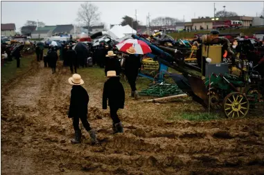  ?? AP PHOTO/MATT ROURKE ?? People walk in mud during an auction at the 56th annual mud sale to benefit the local fire department in Gordonvill­e Saturday. Mud sales are a relatively new tradition in the heart of Pennsylvan­ia’s Amish country, going back about 60years and held in early spring as the ground begins to thaw but it’s too early for much farm work.