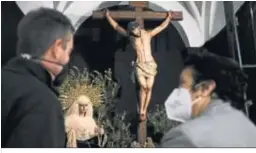  ??  ?? Dos feligreses observan la imagen de Cristo crucificad­o.