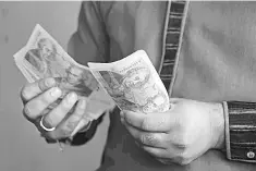  ??  ?? Foreign currency dealer counting British pound notes at a remittance shop in the Pakistani Kashmir city of Mirpur, which is known as ‘Little England.’ If all goes as scripted, the bank will hike borrowing costs in the coming week for the first time in...