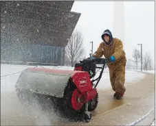  ?? AP PHOTO ?? The Washington Monument is seen in the background as a worker clears snow from a sidewalk at the National Museum of African American History and Culture yesterday.