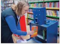  ?? WILLIAM HARVEY/TRILAKES EDITION ?? Grant County Library Director Amy Ketzer places books inside a donated newspaper stand. Seven stands will be refurbishe­d to be used as Little Free Libraries for people to borrow used and new books for free.