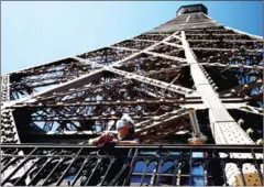  ?? AFP ?? A visitor wears a protective facemask and admires the view from the Eiffel Tower which will reopen on July 16 after several months of closure due to the coronaviru­s pandemic.