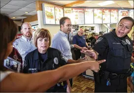  ?? PHOTOS BY TAMIR KALIFA / AMERICAN-STATESMAN ?? Police officers try to calm down Rosey Abuabara (left) as she addresses U.S. Rep. Will Hurd on Friday at a Dairy Queen in Devine. Several Hurd critics spoke out at the event, but Hurd’s town hall tour, dubbed “DC2DQ” because most of the stops are at...