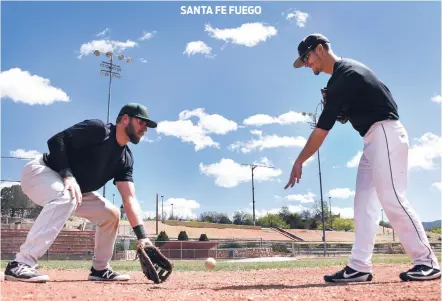  ?? PHOTOS BY CLYDE MUELLER/THE NEW MEXICAN ?? From left, Fuego first baseman David Stone and pitcher Dylan Norris practice a fielding drill Tuesday at Fort Marcy Ballpark. Norris previously played baseball at New Mexico Highlands University.