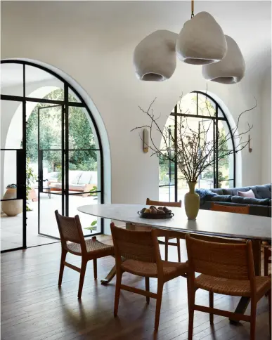  ??  ?? DANS LA SALLE À MANGER, autour d’une table ovale en bronze avec plateau en marbre de Carrare (BDDW), des chaises de Hans Wegner. Au- dessus, la sculpture lumineuse Fertility Form du designer Rogan Gregory, 2018 (R & Company). Dans le coin salon, un canapé Turkish Sofa (George Smith). Appliques Raku-Yaki (Emmanuelle Simon).