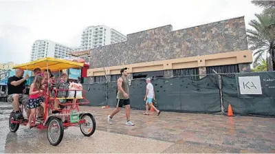  ?? JOHN MCCALL/SOUTH FLORIDA SUN SENTINEL ?? Pedestrian­s pass by Nick’s Bar and Grill on Tuesday, which has been undergoing renovation­s, but could reopen next month in Hollywood.