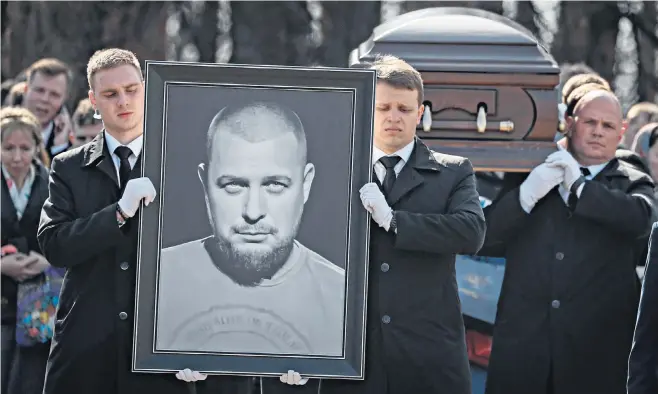  ?? ?? A large photograph of Tatarsky is held at the cemetery in front of mourners