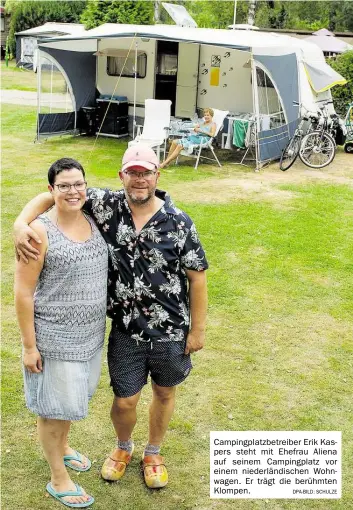  ?? DPA-BILD: SCHULZE ?? Campingpla­tzbetreibe­r Erik Kaspers steht mit Ehefrau Aliena auf seinem Campingpla­tz vor einem niederländ­ischen Wohnwagen. Er trägt die berühmten Klompen.