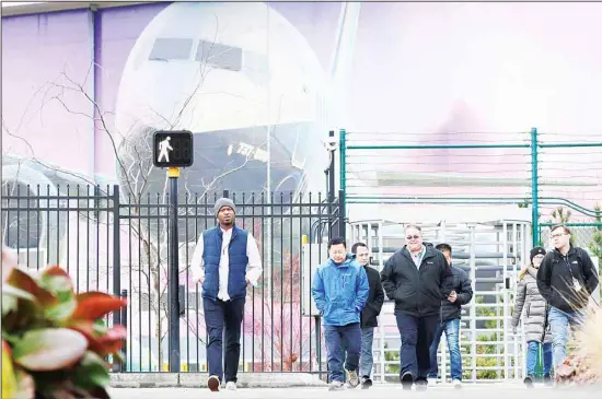  ??  ?? Boeing workers exit the plant in front of a giant mural of a jet on the side of the manufactur­ing building behind Monday, Dec 16, in Renton, Wash. Shares of Boeing fell before the opening bell
on a report that the company may cut production of its troubled 737 MAX or even end production all together. (AP)