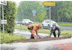  ?? FOTO: HEIKO LEHMANN ?? Diese Helfer versuchten vor dem Auersmache­r Ortseingan­g an der B 51 die heranström­enden Wassermass­en mit einem Brett umzuleiten.