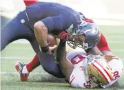  ?? BETTINA HANSEN/THE SEATTLE TIMES ?? Seahawks quarterbac­k Russell Wilson sustains a knee injury while being pulled down by Eli Harold in the second half.