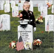  ?? CAROLYN KASTER/AP ?? Christian Jacobs, 5, pauses at his dad’s grave at Arlington National Cemetery in Virginia to honor him on Memorial Day. Marine Sgt. Christophe­r James Jacobs died in 2011.