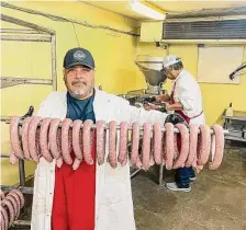  ?? ?? Sammy Palomarez, front, and Sam Palomarez, back, prepare venison sausage for the smoker at Dozier’s BBQ.