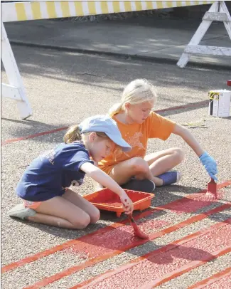  ?? Brodie Johnson • Times-Herald ?? No one is too young to help paint crosswalks in downtown Forrest City as part of the crosswalk project. Merritt Higginboth­om, left, and Fuller Higginboth­om join Smith Insurance Company employees and others this morning at the Hill and Rosser streets intersecti­on to help paint an American Flag on the crosswalk.