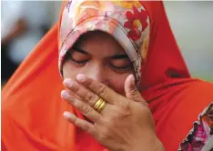  ??  ?? A woman wipes her tears as she offers prayers to loved ones at a mass grave in Aceh yesterday to mark the tsunami which devastated Aceh province 12 years ago in one of the worst natural disasters in human history. — AFP