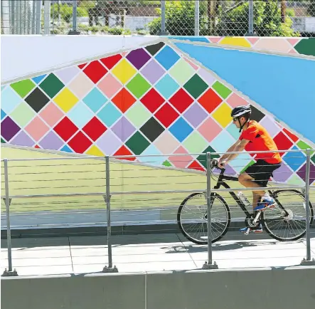  ?? JIM WELLS ?? A cyclist rides past an outdoor painting on 4th St SE in Calgary on Saturday. Proposed changes to the city’s public art policy could see a shift toward using local artists instead of outsourcin­g projects, and better consultati­on with Calgarians and Indigenous groups.