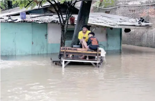  ?? Agence France-presse ?? Residents sit outside their flooded home in Jakarta on Tuesday. Heavy rain inundated parts of the Indonesian capital.