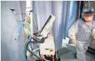  ?? JOHN MINCHILLO/AP ?? A nurse pulls a ventilator into an exam room where a patient with COVID-19 went into cardiac arrest in Yonkers, N.Y.