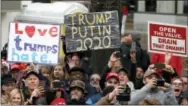  ?? THE ASSOCIATED PRESS ?? People hold signs as they line the inaugurati­on parade route in Washington on Friday as Donald Trump passes in his motorcade after being sworn in as the 45th president of the United States.