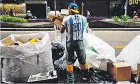  ?? ?? Un reciclador de cartón busca mercancías entre la basura en la avenida Corrientes de Buenos Aires. Archivo AFP