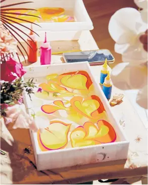  ?? ?? A tray of water with acrylic paint for dipping flowers.