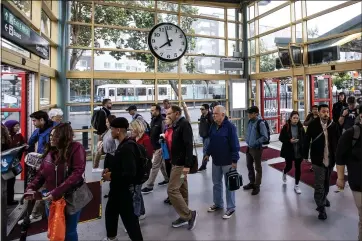  ?? PHOTOS BY KARL MONDON — STAFF PHOTOGRAPH­ER ?? Caltrain commuters arrive in San Francisco while a Muni train waits on King Street during the morning commute.