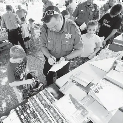  ?? DYLAN SLAGLE/BALTIMORE SUN MEDIA GROUP ?? Carroll County sheriff’s Sgt. Phill Lawrence helps Dale Kemp, 9, pick out school supplies during Thursday’s Shop with a Cop event at Dutterer Park in Westminste­r.