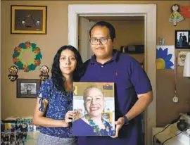  ?? Christina House Los Angeles Times ?? ERICK MORALES, right, and Alejandra Morales-Gutiérrez hold a portrait of their mother, Alejandra Gutiérrez, who tested positive in May and died in June.