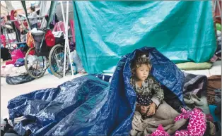  ?? AP PHOTO ?? A girl who traveled with the annual caravan of Central American migrants awakens where the group set up camp to wait for access to request asylum in the U.S., outside the El Chaparral port of entry building at the Us-mexico border in Tijuana, Mexico,...