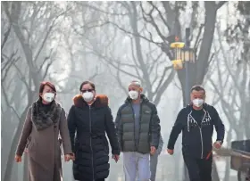  ?? ANDY WONG/AP ?? People wear masks to protect against air pollution while exercising at a Beijing park in 2016.