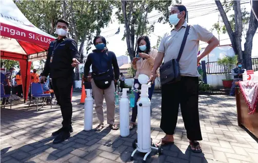  ?? GUSLAN GUMILANG/JAWA POS ?? KHUSUS YANG POSITIF COVID-19: Warga antre mengisi oksigen di UPT PPD di Jalan Pahlawan 41, Sidoarjo, kemarin. Mereka bisa mendapatka­n oksigen gratis asal mengisi formulir.