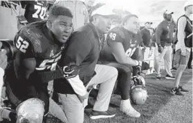  ?? JULIO CORTEZ/AP ?? Navy coach Ken Niumatalol­o, center, kneels with defensive end Denzel Polk (52) and defensive lineman Jackson Pittman (99) as they watch the final play against Air Force last October. Niumatalol­o is seeking his 100th career coaching victory on Saturday.