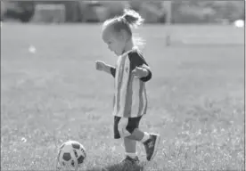  ??  ?? Two-year-old Livia Bray takes aim with a kick. Children as young as 18 months old are learning soccer.