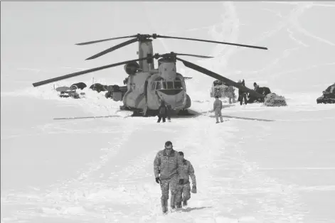  ?? MARK THIESSEN/AP ?? CAPT. COREY WHEELER (FRONT), COMMANDER OF B COMPANY, 1st Battalion, 52nd Aviation Regiment at Fort Wainwright, Alaska, walks away from a Chinook helicopter that landed on the glacier near Denali, on April 24, 2016, on the Kahiltna Glacier in Alaska. The U.S. Army helped set up base camp on North America’s tallest mountain. The U.S. Army is poised to revamp its forces in Alaska to better prepare for future cold-weather conflicts, and it is expected to replace the larger, heavily equipped Stryker Brigade there with a more mobile, infantry unit better suited for the frigid fight, according to Army leaders.
