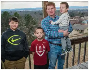  ?? WILLIAM HARVEY/RIVER VALLEY & OZARK EDITION ?? Morrilton Mayor Allen Lipsmeyer, standing on the porch of his home, enjoys a day off with his grandsons Drake Bradley, 3, (held by Lipsmeyer) and Andrew Thompson, 9, standing next to him, as well as neighbor Hunter Hulsey, 12, far left. Lipsmeyer said...