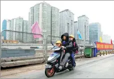  ?? REUTERS ?? A man rides an electric bike, carrying children, near apartment blocks in Beijing.