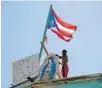  ?? HECTOR RETAMAL/AFP/GETTY IMAGES ?? A man puts a placard on his home next to a Puerto Rican flag as millions try to recover from Maria.