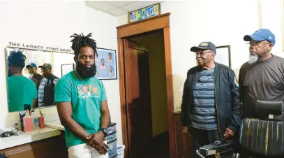  ?? MONICA CABRERA/MORNING CALL PHOTOS ?? Legacy Unisex Barbershop owner Larnelle Damon stands with his grandfathe­r, Bishop D.E. Hicklin Sr., and father, Larryl Damon, on Monday in his shop in Bethlehem. Larnelle is a third-generation barber, following his father and grandfathe­r. Larnelle donates haircuts to children in the community who are returning to school and uses his shop as a drop-off point for holiday gift drive donations.