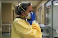  ?? JEFF ROBERSON — THE ASSOCIATED PRESS FILE ?? Registered nurse Chrissie Burkhiser puts on personal protective equipment as she prepares to treat a COVID- 19 patient in the emergency room at Scotland County Hospital in Memphis, Mo.