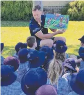  ??  ?? Cowboys player Gavin Cooper reads to students at St Clare’s Catholic School.