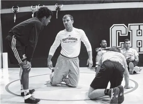  ?? STAFF PHOTO BY DOUG STRICKLAND ?? UTC wrestling coach Kyle Ruschell, center, talks with Alonzo Allen during the Mocs' practice at Maclellan Gymnasium on Wednesday. Allen won the Southern Conference championsh­ip in the 125-pound division last season.