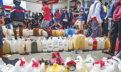  ?? AFP ?? ■ People line up their containers to collect gasoline at a petrol station in Palu in Central Sulawesi yesterday, four days after the earthquake and tsunami hit the area. The Indonesian government said the death toll on the island of Sulawesi had risen to 1,234.